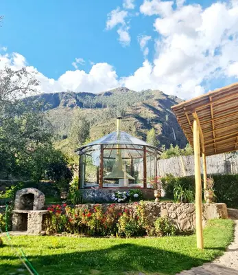 a greenhouse in a garden with mountains in the background at Arins House in Cusco