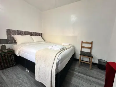 a bedroom with a large bed and a chair at Habitaciones para Turistas en Zona Tranquila de Cusco in Cusco