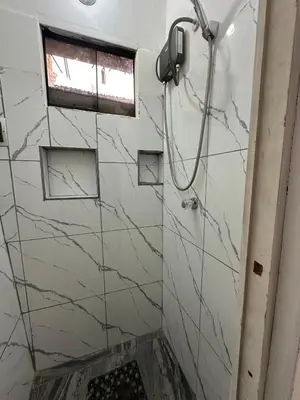 a shower in a bathroom with marble walls and a window at Habitaciones para Turistas en Zona Tranquila de Cusco in Cusco