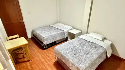 a small room with two beds and a wooden floor at Habitación tranquila a 15 min de Plaza Norte in Lima