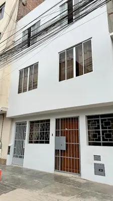 a white building with red doors and windows at Habitación tranquila a 15 min de Plaza Norte in Lima