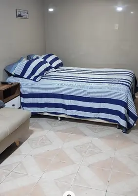 a bedroom with a bed with a blue and white blanket at Monoambiente a 20 minutos del Aeropuerto, moderno y privado in Lima