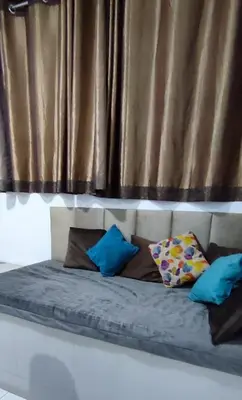 a bed with blue pillows in front of a curtain at Monoambiente Parque Naranjal B, a 20 minutos del Aeropuerto - Hasta 3 huéspedes in Lima