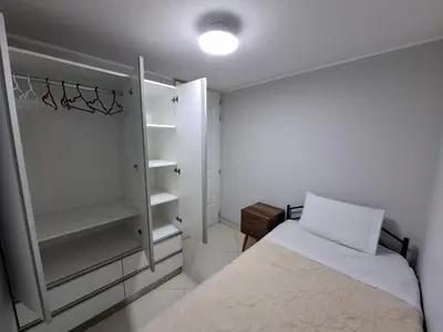a white bedroom with a bed and white shelves at Apartamento en condominio cerca a Plaza Norte in Lima