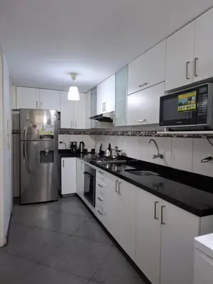a kitchen with white cabinets and a stainless steel refrigerator at Apartamento en condominio cerca a Plaza Norte in Lima