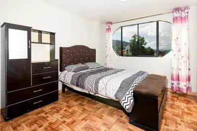 a bedroom with a bed and a dresser and a window at Alameda Suite Ayacucho in Ayacucho