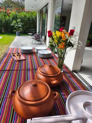 a table with two pots and plates and a vase of flowers at La Morada del Sol in Cieneguilla