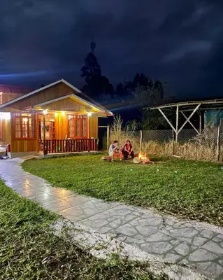 two people sitting around a fire in a yard at night at Cabañas Don Ceferino in Palmira