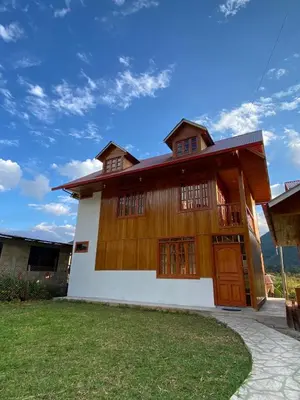 a house with a wooden facade with a grass yard at Cabañas Don Ceferino in Palmira