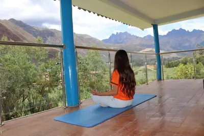a woman sitting on a yoga mat looking out at the mountains at Country house in nature in Sacred Valley in Huayllabamba