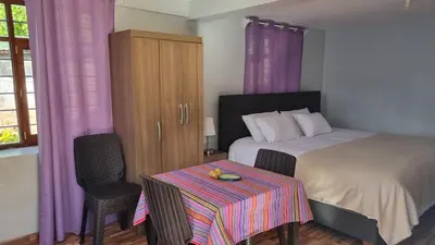 a bedroom with a bed and a table and purple curtains at Cottage in nature in Sacred Valley with mountain views in Huayllabamba