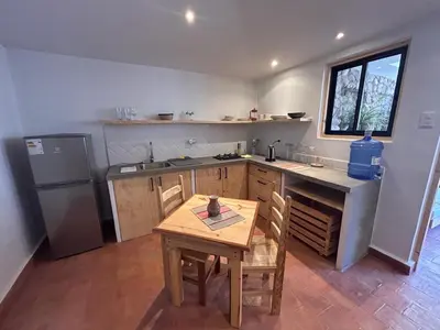 a small kitchen with a table and a refrigerator at Chaqra in Urubamba