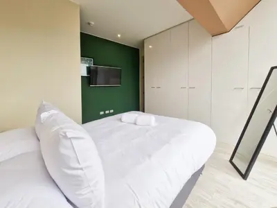 a bedroom with a white bed and a green wall at Spacio 299 by Geko in Lima