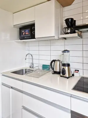 a white kitchen with a sink and a microwave at Spacio 299 by Geko in Lima