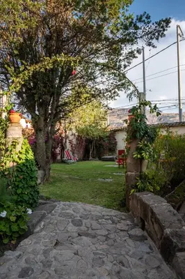 a garden with a tree and a stone walkway at Hospedaje La Florida in Urubamba