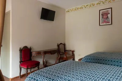 a bedroom with a bed and a tv on the wall at Hospedaje La Florida in Urubamba