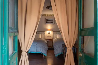 a bedroom with two beds with curtains in it at Hospedaje La Florida in Urubamba