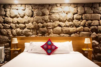 a bedroom with a bed and a stone wall at Casa Amará in Cusco