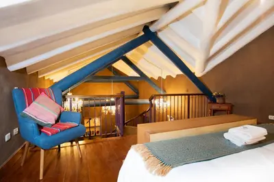 a bedroom with a bed and a blue chair at Casa Amará in Cusco