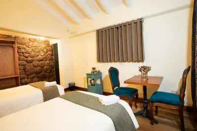 a hotel room with two beds and a table and chairs at Casa Amará in Cusco