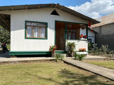 a small white house with a door and flowers at Schütze-Haus in Oxapampa
