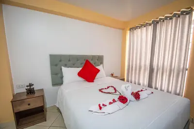 a bedroom with a large white bed with red pillows at VILLA andina cusco in Cusco