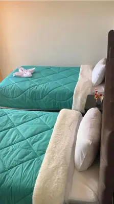 a bedroom with two beds with green sheets and pillows at VILLA andina cusco in Cusco
