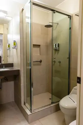 a glass shower in a bathroom with a toilet at Palmetto Hotel Business La Perla in Lima