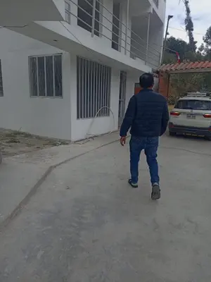 a man standing outside of a house with a hose at Hotel Campestre Corina