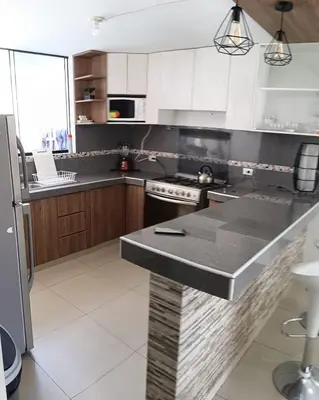 a kitchen with white cabinets and a black counter top at Un house ica in Ica