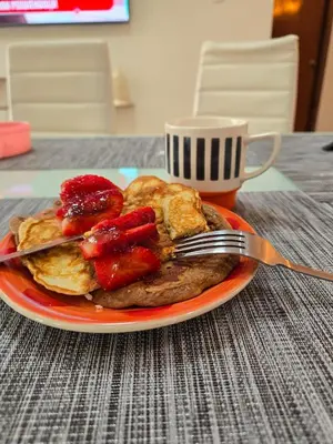 a plate of pancakes with strawberries and a cup of coffee at Un house ica in Ica