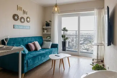 a living room with a blue couch and a large window at Urbana Perú Tempo in Lima