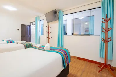 two beds in a room with blue curtains at Inkary Hotel Machupicchu in Machu Picchu