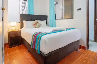 a bedroom with a large white bed with a mirror at Inkary Hotel Machupicchu in Machu Picchu