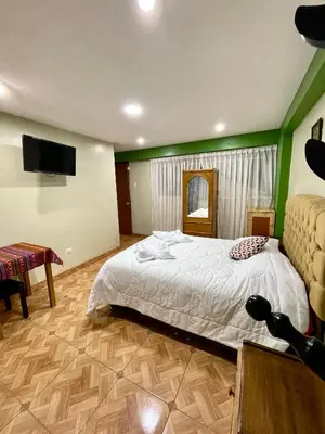 a bedroom with a bed and a flat screen tv at TORIBIANS Hotel in Chinchero