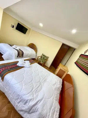 a hotel room with two beds and a television at TORIBIANS Hotel in Chinchero