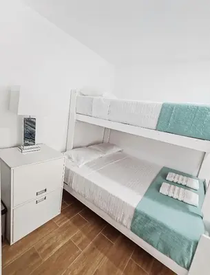 a white bedroom with a bunk bed and a nightstand at Confortable con vista al mar de Naplo, Pucusana in Pucusana