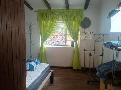 a bedroom with a bed and a window with yellow curtains at Yuntawasi Cozy mini Ollantaytambo in Ollantaytambo