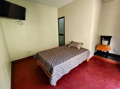 a bedroom with a bed and a flat screen tv at Casa familiar con parrilla, piscina, WiFi y cesped