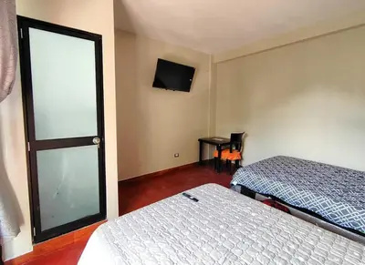 a room with two beds and a tv and a window at Casa familiar con parrilla, piscina, WiFi y cesped