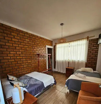 a bedroom with two beds and a brick wall at Hotel Nuestro Amo in Sayán