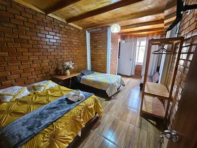 a bedroom with two beds and a brick wall at Hotel Nuestro Amo in Sayán
