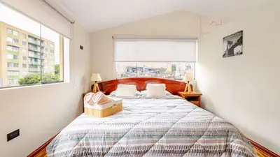 a bedroom with a large bed with a large window at Loft equipado y acogedor con Terraza en Matellini in Lima