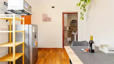 a kitchen with a refrigerator and a table with a bottle of wine at Loft equipado y acogedor con Terraza en Matellini in Lima