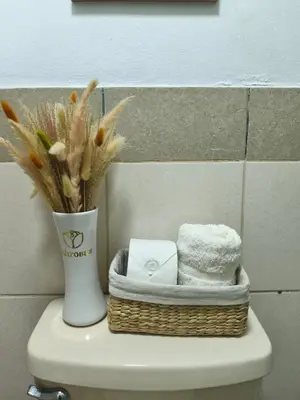a basket of towels and a vase on top of a toilet at Habitación Pequeña dentro departamento compartido 402 in Lima