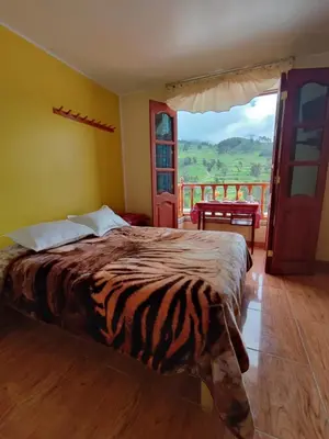 a bedroom with a bed and a balcony with a view at Hotel Tambo del Inca in Cajatambo