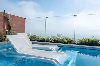 two white chairs sitting on the edge of a swimming pool at Contemporary Great View in Lima