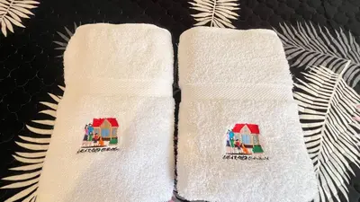 two towels with houses on them on a bed at C4s4 RANCH OXAPAMPA in Oxapampa