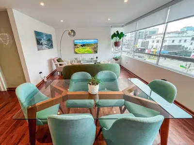 a dining room with a glass table and green chairs at LimaViva A in Lima