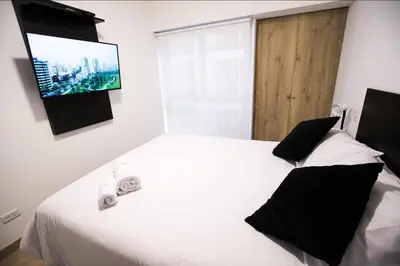 a bedroom with a white bed and a tv on the wall at iStay Atractivo corazón de Miraflores 2 Camas 2 Baños in Lima